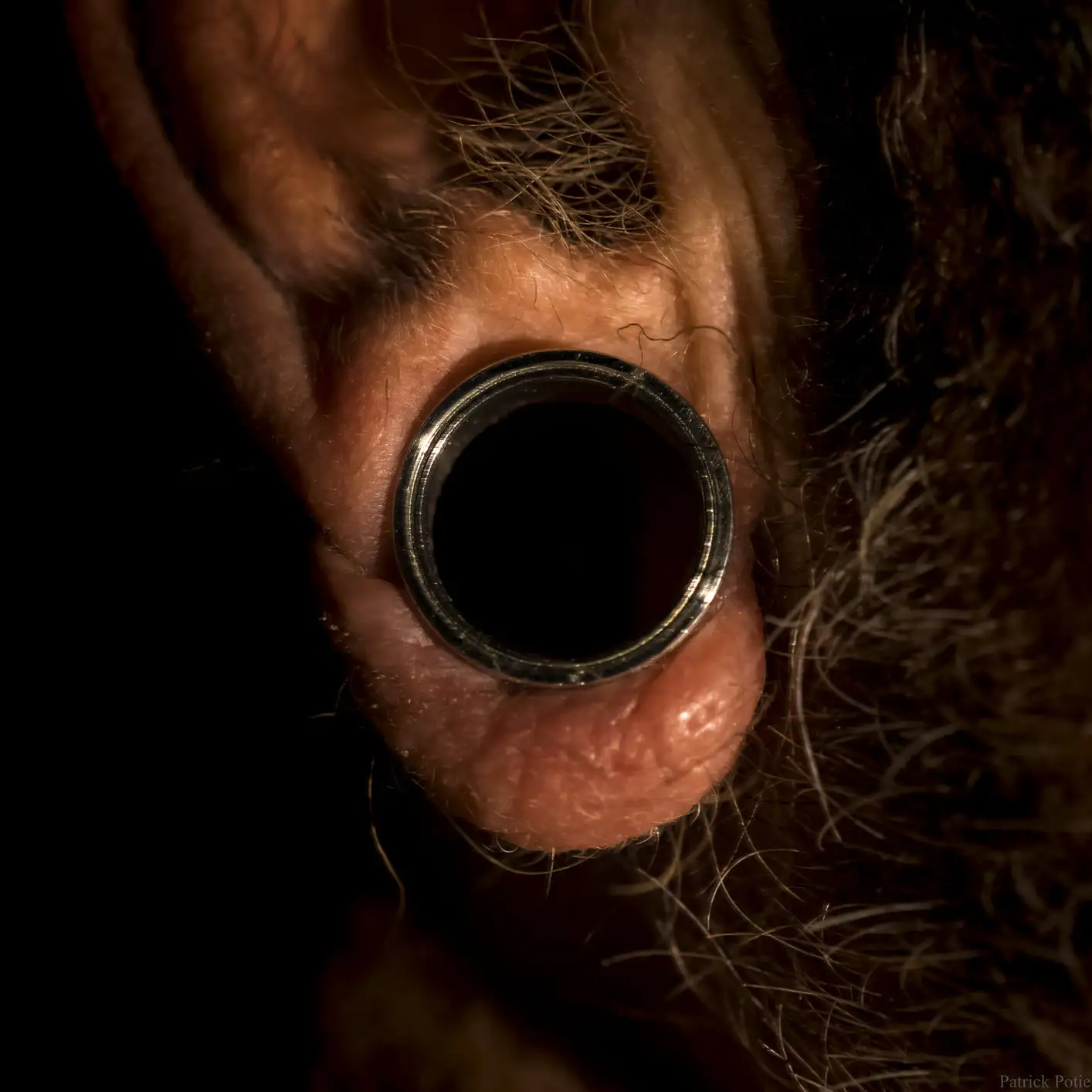 Lobe d'oreille humain présentant un piercing tunnel comme forme de modification corporelle