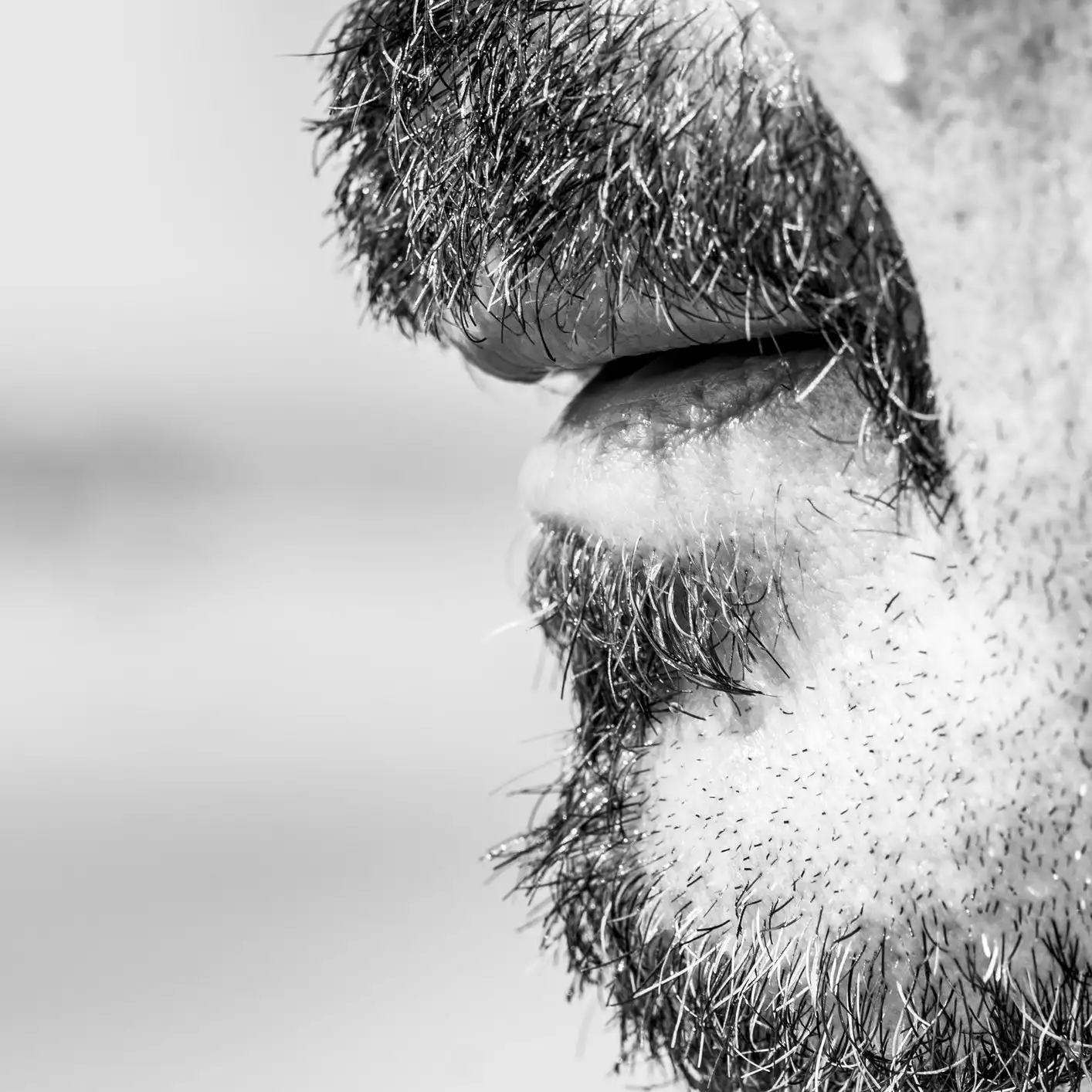 Gros plan en noir et blanc de la bouche, des lèvres et de la barbe naissante d'un homme
