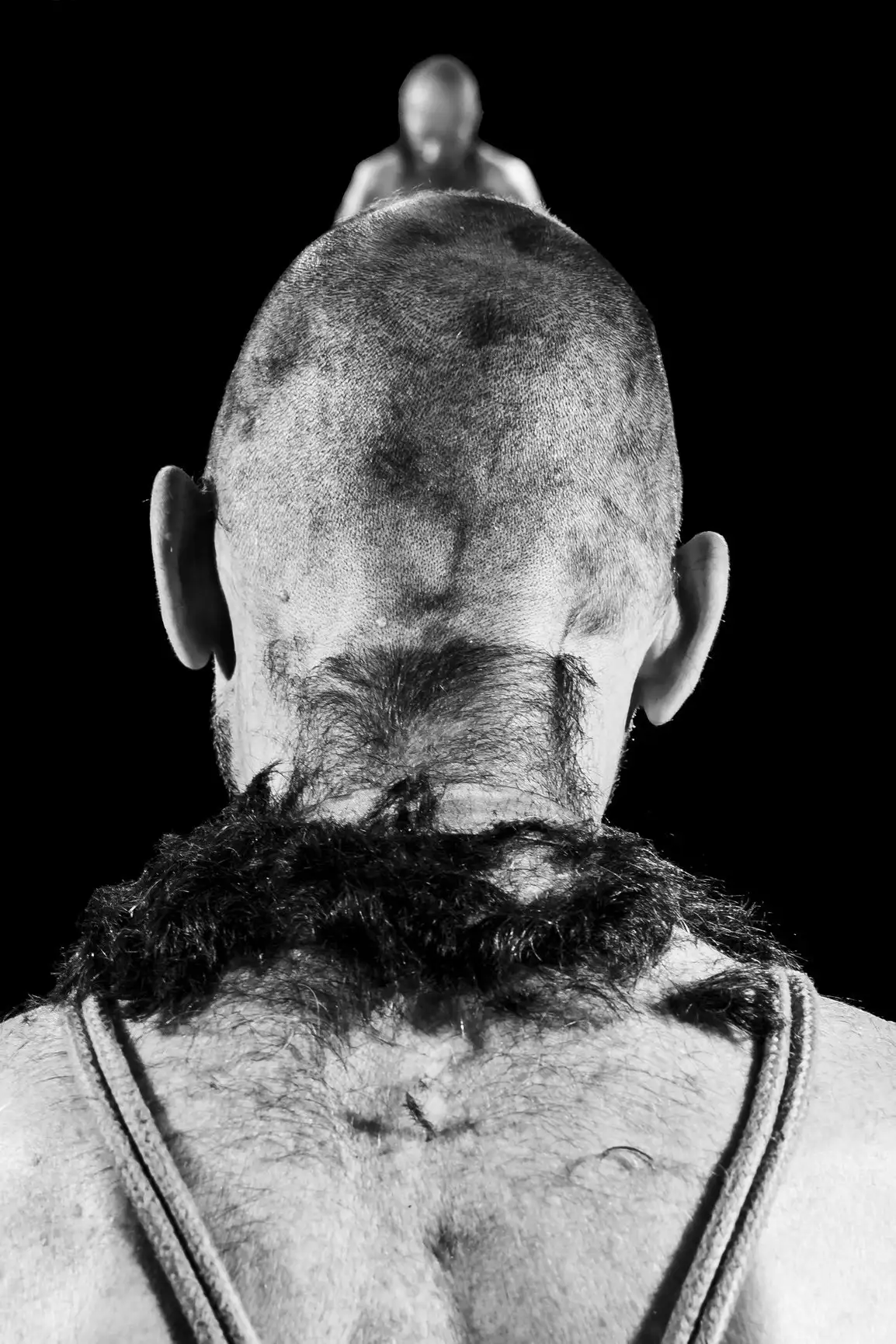 Un homme au crâne rasé avec tout ses cheveux autour de sa nuque