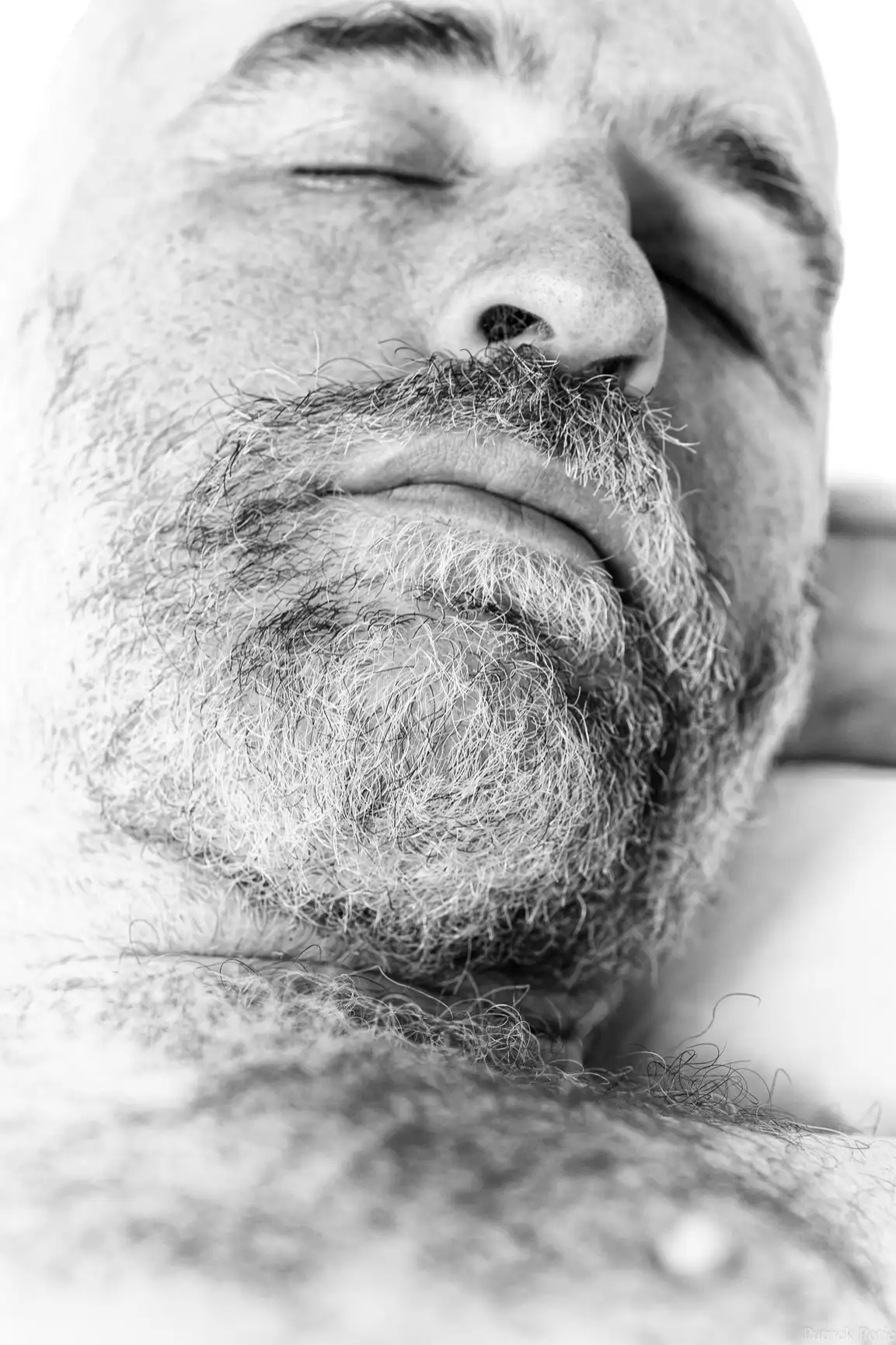 Un homme barbu dort, trouvant calme et sérénité.